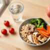 Dieta dla dzieci — zbilansowany posiłek dziecka: kurczak, kasza, brokuły, marchewka, woda i jabłko